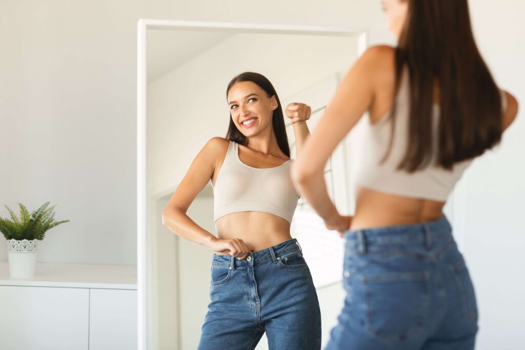 young woman looking into mirror weight loss